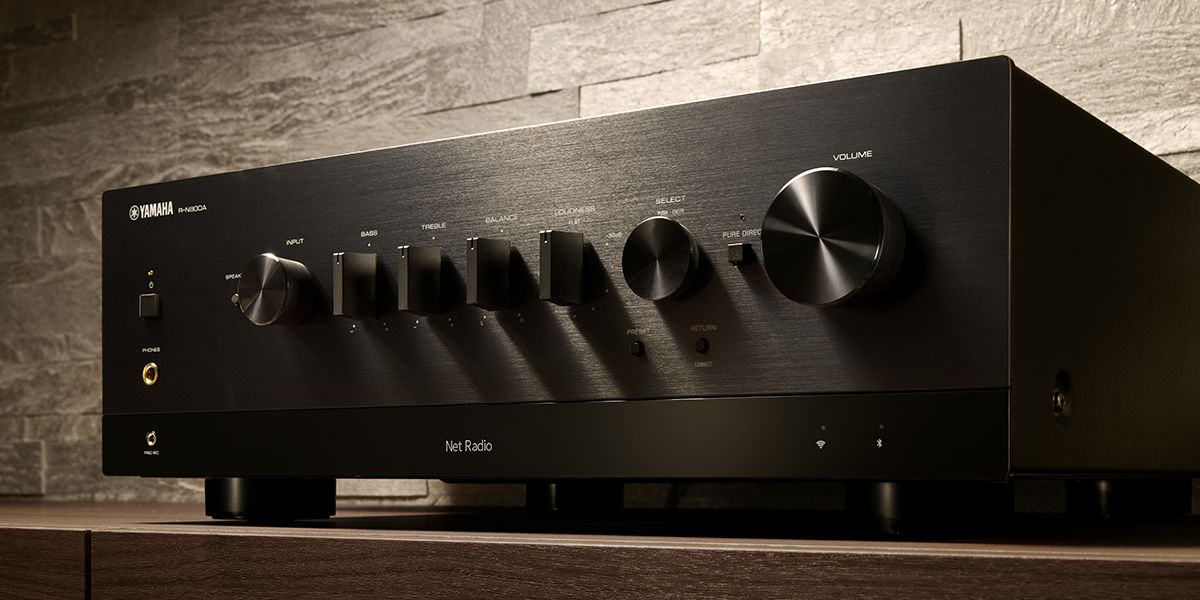 Low-angle studio shot of a black Yamaha R-N800A stereo network receiver with a row of control knobs and a large volume dial, set against a textured stone backdrop.