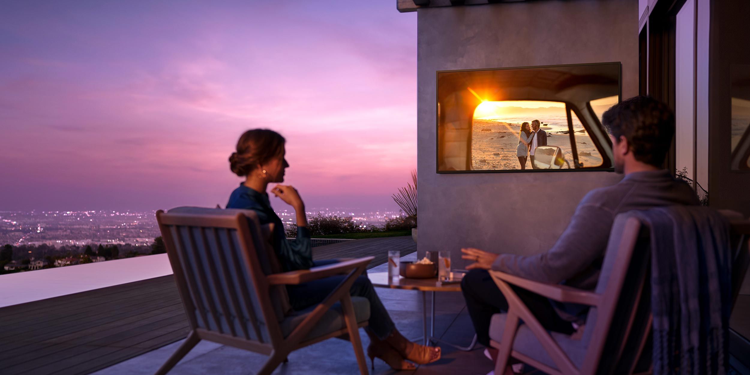 A couple enjoying an outdoor movie experience with a sunset view in the background.